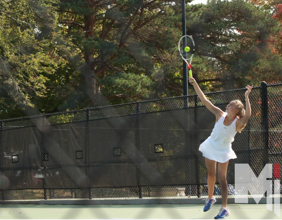Senior Delaney Pepin goes up for a serve during her doubles match.