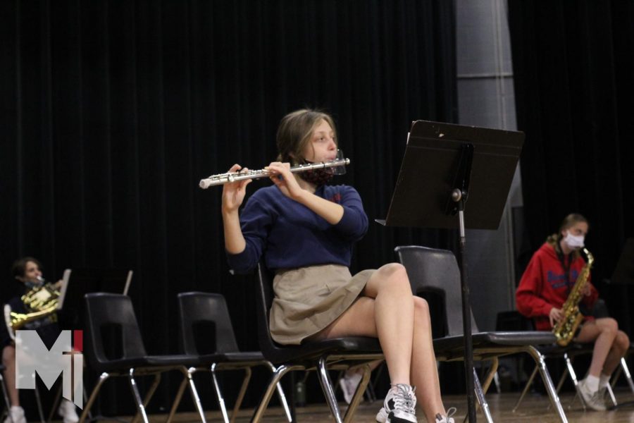 Looking up at band director Tiffany Nesbihal, senior Sarah Hayes plays her flute. 