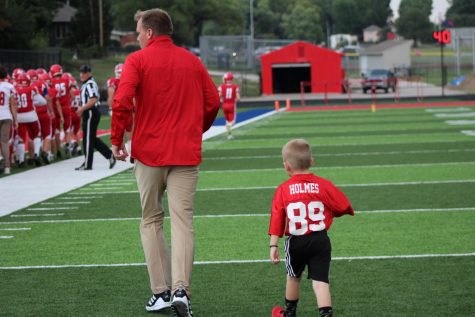 Walking on the field before the game, football coach Jon Holmes’ son Hank Holmes follows his dad as he joins the team before the team’s first home game kickoff. That night, the Stags took their first victory of the season with a final score of 23-20 against rival school Saint Thomas Aquinas.
