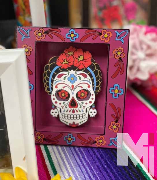 Colorful decorations adorn the Day of the Dead altar set up in the gym foyer. Students and staff were invited to place pictures of their loved ones along with the decorations. 