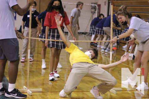 Hands in the air, senior Black Allen demonstrates for the freshman how to get under the limbo stick. Behind him is freshman Jiselle Araiza waiting to go next.