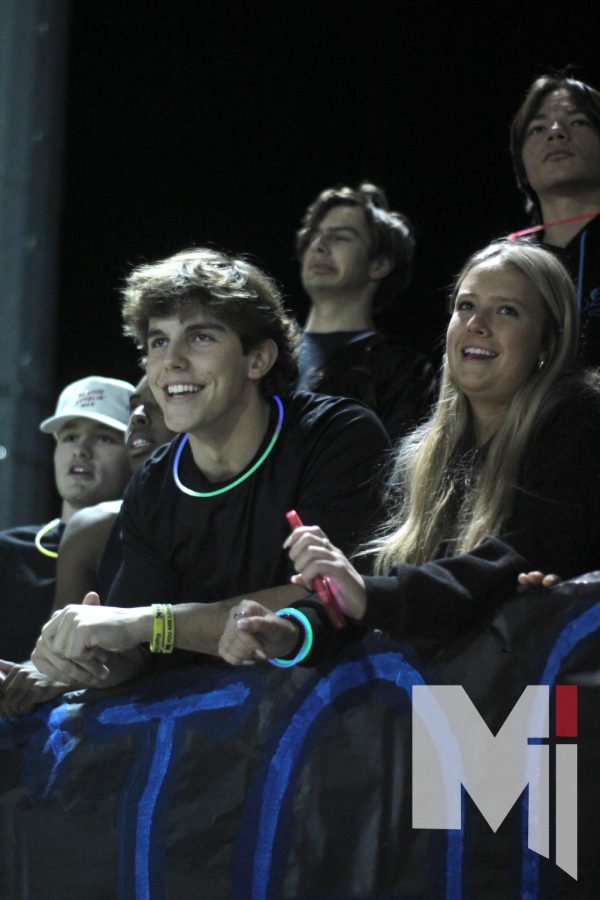 Focusing on the field, seniors Jack Elder and Aniston Faul cheer on the team during the third quarter. The theme for the game was glow out.