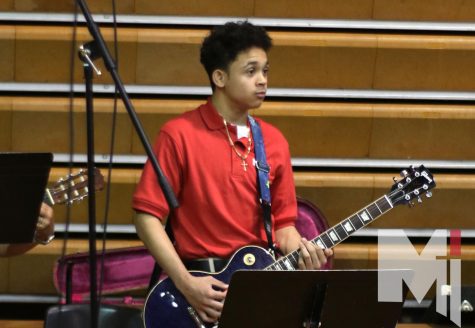Foot on the speaker, freshman Lucien Slater holds his guitar on Aug. 31. This was Slaters first time playing the guitar during a Miege all- schoo Mass. Well I love it, Slater said. “If it’s at Church then I think I’m playing for God.”