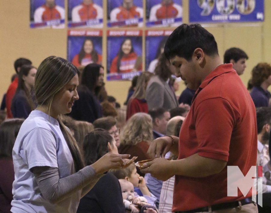 Dressed in the Perrini herd shirt, junior Paige Calderon receives communion from senior Anthony Arroyo on Dec. 8. An all-school Mass was held to commemorate the 10th anniversary of former campus minister Mary Perrini’s death. “This Mass was one to remember,” Calderon said. “Having her family members there brought more importance to the Mass.”