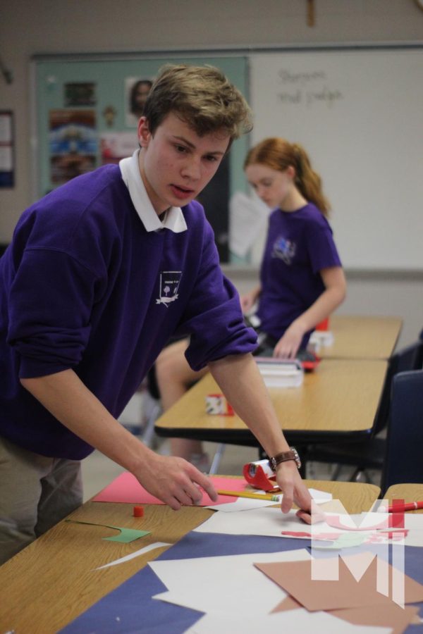 Gluing down reindeer, sophomore Henry Holm helps out with theology teacher Patricia Arnold’s door decorations on Dec. 1. The theme for the Tylicki herd was Christmas movies.  
