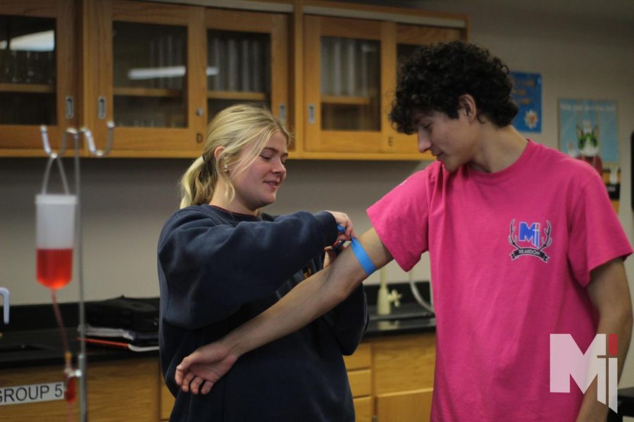 Extending his hand, senior Alexander Murphy helps sophomore Jane Werner identify veins on a human body on Dec. 9. The Principles of Biomedical Science class learned how to properly draw blood from latex arms from nurse Malisa McEachen. 