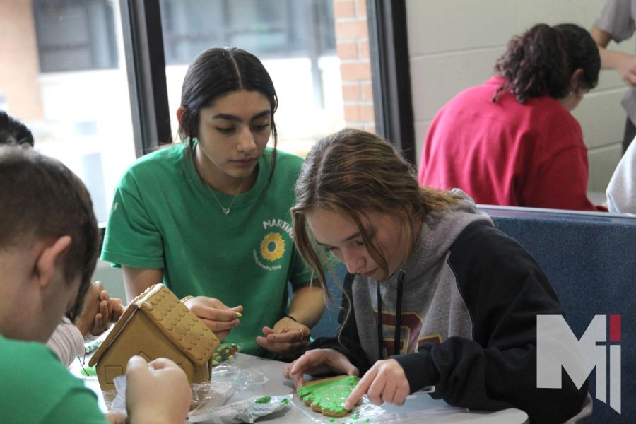 Martina herd members sophomores Shae Coughlan and Isabella Franco frost a Christmas tree cookie to place on their gingerbread house on Dec. 9. During the Christmas social, herds competed in gingerbread decorating competitions. 