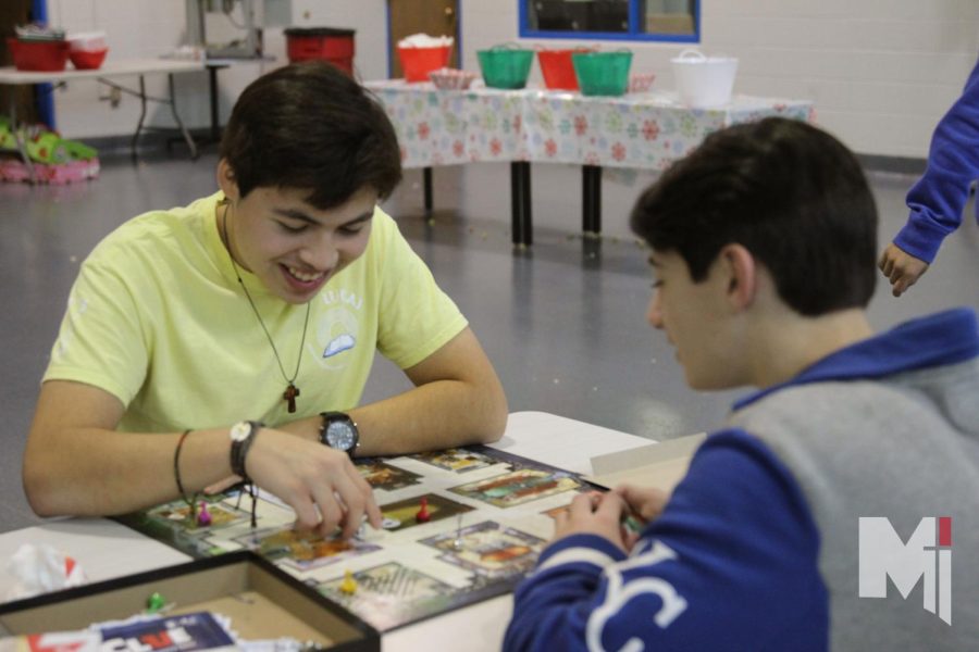 At the Christmas social, freshmen David Zavala and Adam Marsh play the board game Clue. During the social, students were able to play games and watch a movie in the auditorium on Dec. 9. “It was really fun to be with everyone and see your friends at the end of the day,” Zavala said. 