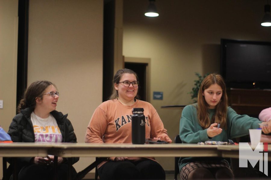 Gathered around tables before small group discussion, freshman Annie McGuire and sophomore Clare Hansen distribute pens and paper to write down any questions the members may have. Each Sunday, the Holy Trinity Life Teen meets after 5 p.m. Mass.
