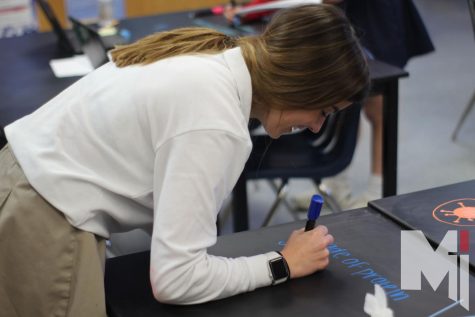 Writing on a desk for a lab in Principles of Biomedical Science, senior Ava Forton laughs at her writing. In the lab students took notes on the table with chalk markers. “My favorite part about biomed is how interactive the labs are,” Forton said. 
