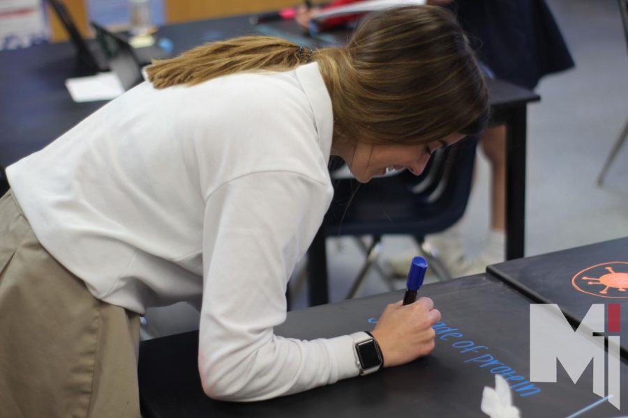 Writing on a desk for a lab in Principles of Biomedical Science, senior Ava Forton laughs at her writing. In the lab students took notes on the table with chalk markers. “My favorite part about biomed is how interactive the labs are,” Forton said. 
