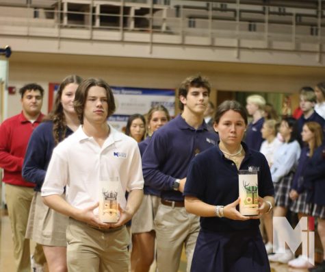 At the start of Mass, senior herd leaders walk in holding their herd candles. The senior herd leaders passed the candles to the new herd execs in the chapel on April 12.