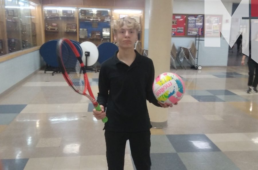 Freshman Joseph Charles holds a tennis racket and volleyball