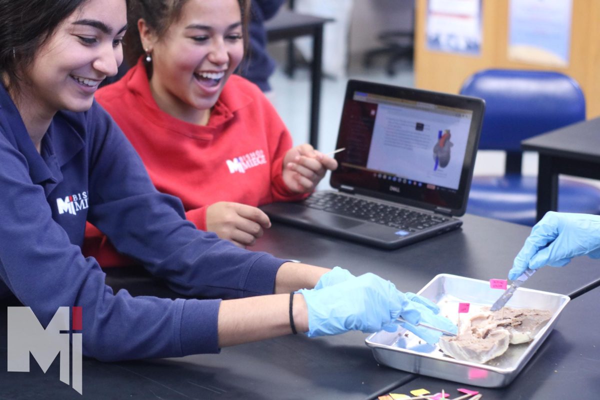 Seniors Carrina Villanueva and Gianna Collins laugh while carefully dissecting a sheep heart. The lab expanded Villanueva’s knowledge in the medical field. “It was really cool being able to see how sheep hearts are related to human hearts.”  