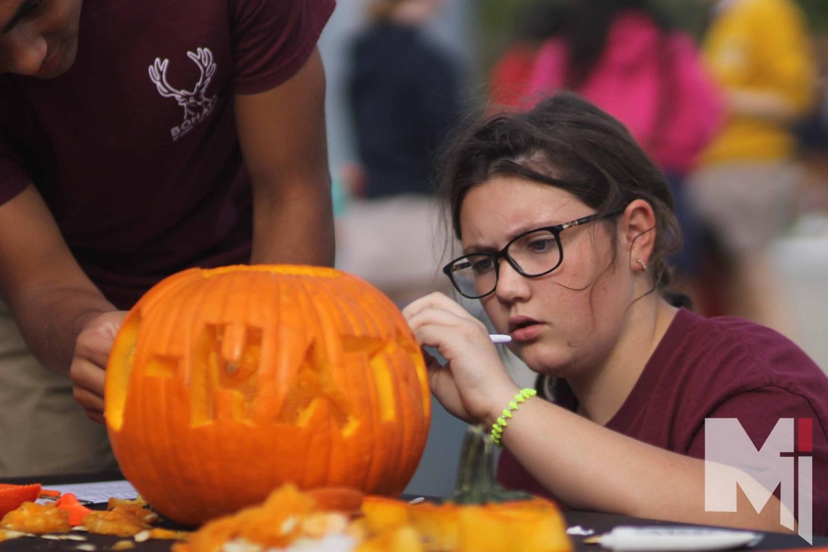 At the herd carving competition, freshmen Evelyn Howard carves a pumpkin. 