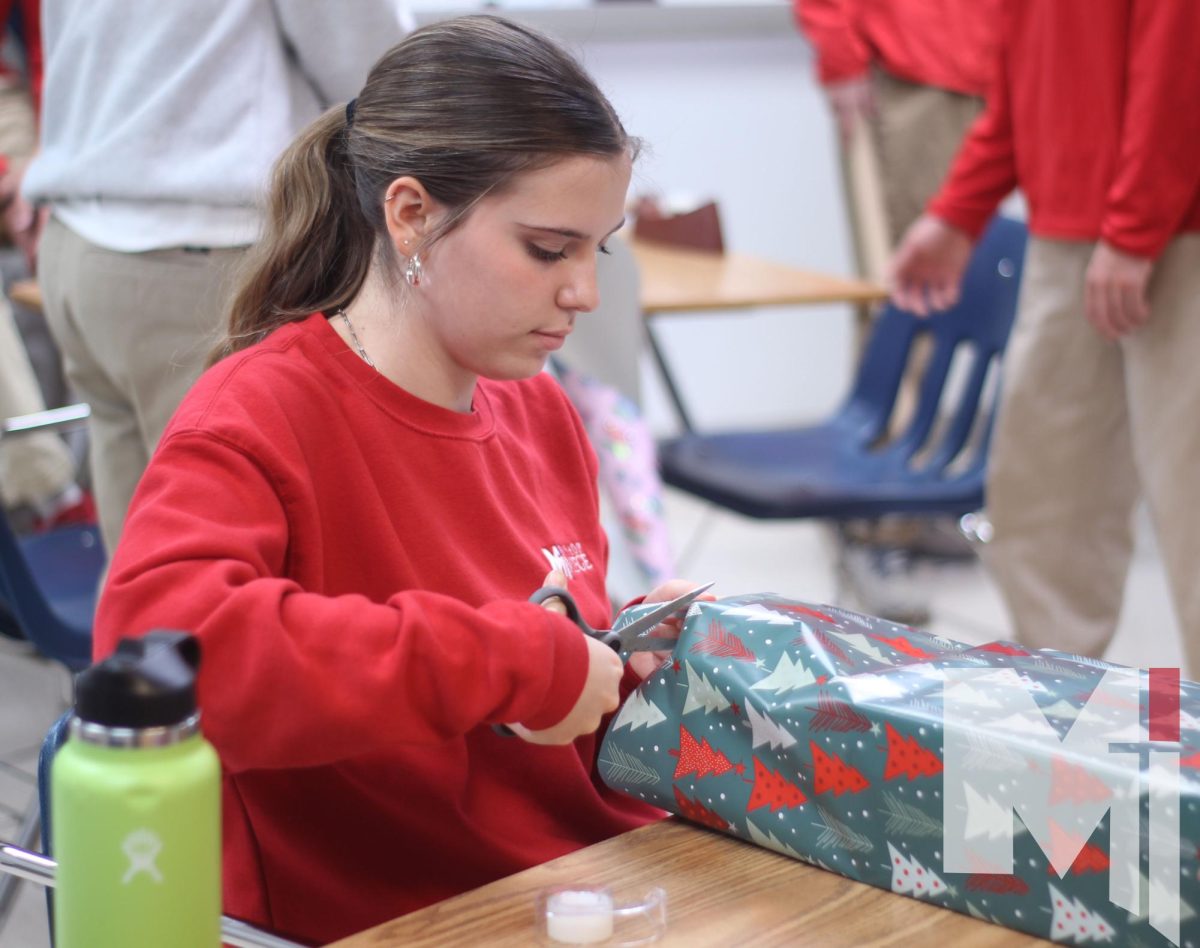 Serving the community, freshman Samantha Mohlman enjoys her first Don Bosco wrapping party. Students took part in wrapping presents and putting them under the Christmas trees for their herds. “It makes me feel very good knowing that I can help people in need,” Mohlman said. “I am very grateful that I am in a position where I can help people and make a few peoples Christmas a little better this year.” 