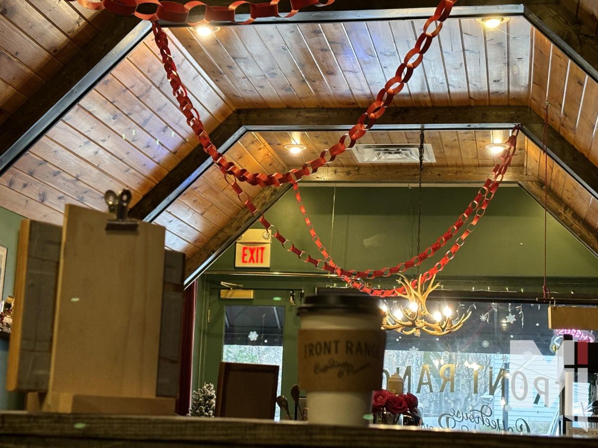 A coffee sits on a ledge inside of Front Range Cafe, Holiday decorations adorn the ceiling.