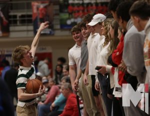 Cheering on the team, senior Connor Neenan stands in the front row with his fellow seniors to help lead and pump up the student section at the boys basketball game against Rockhurst.  “Especially this year watching my friends that Im close with play makes it even more exciting,” Neenan said. “I’ve always gone to basketball games, but getting to help lead is so much fun.”
