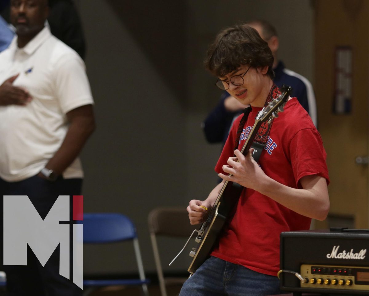 Rocking out, freshman Alex McBride plays the national anthem on his electric guitar. After talking to head football coach Jon Holmes, McBride received permission to play -- a first for the season. “This is my eighth year playing the guitar, and I love it,” McBride said. “I want to keep playing the guitar during the assemblies and other stuff like that.”