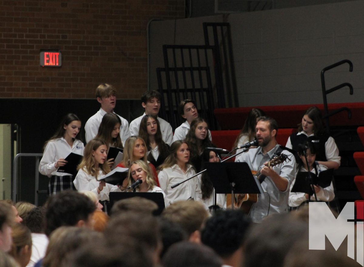 Filled with emotion, senior Emma Masters sings at the Oct. 16 all-school mass along with the choir. “I love to sing and I love Jesus even more, so any time I get to do both of those things is always a great thing,” Masters said. “I like that all of our voices come together, kind of how God wants us to live among each other.”