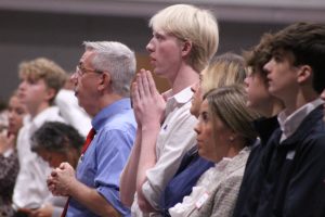 Standing next to Campus Minister Bill Creach, senior Gannon Cole presses his palms in prayer as he shows reverence during an all school mass.