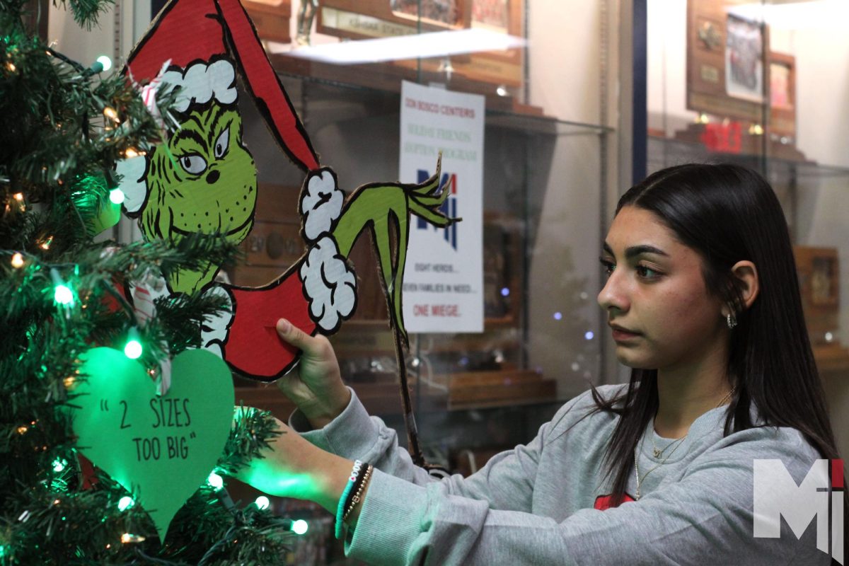 Senior Bella Franco helps decorate the Martina herd Christmas tree during the annual “Red Bag” event on Dec.5. During Red Bag, students adopt families from the Don Bosco Center and help provide essential items to families in need.      “‘Red Bag’ gets all the community involved, and really makes us think more about what Christmas is really about,” Franco said. “This tradition is my favorite part , it has such deep meaning.”